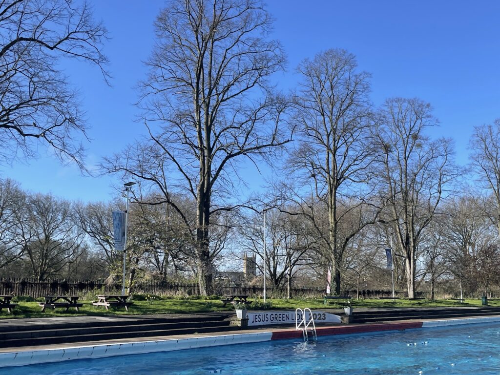 A designated area for entering an outdoor pool is marked off in red with a white ladder and a bright red sign against white paint that reads Jesus Green Lido 2023.