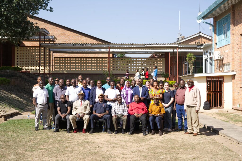 A large group of people arranged in rows, with the first row seated, pose for a photo in a courtyard.