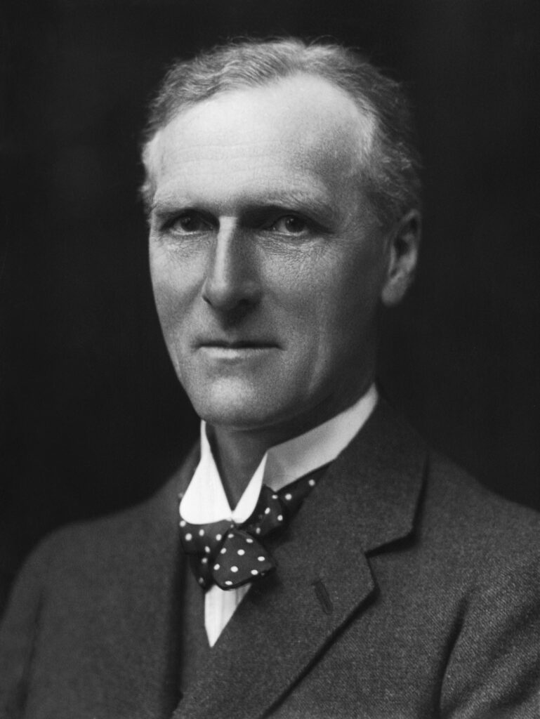 A black-and-white portrait depicts a man in a suit and a bowtie.
