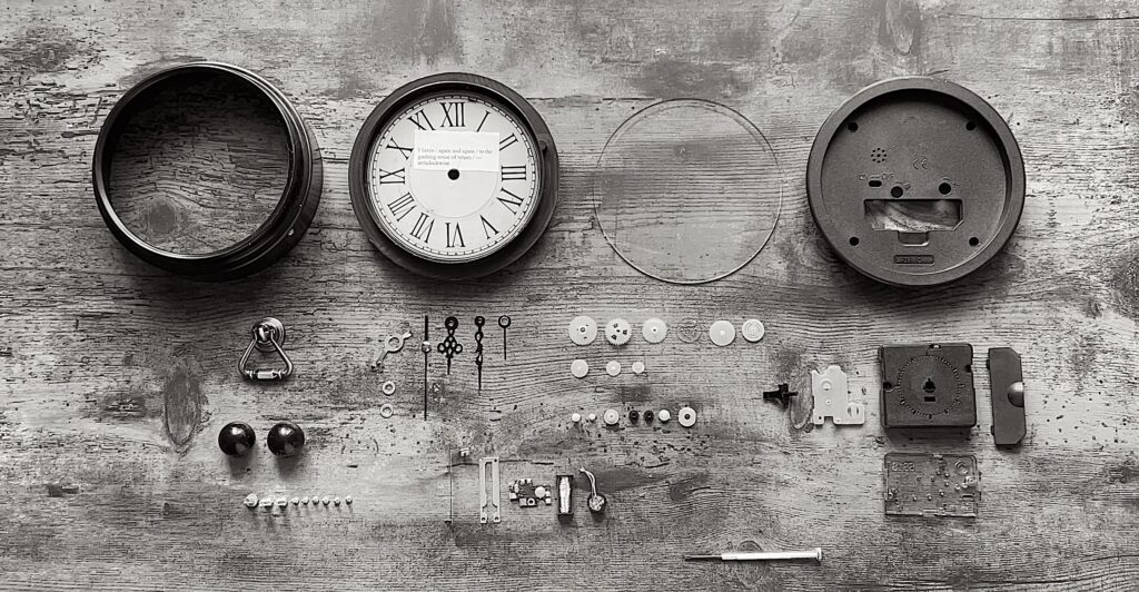 Parts of a wall clock lie on a table disassembled.